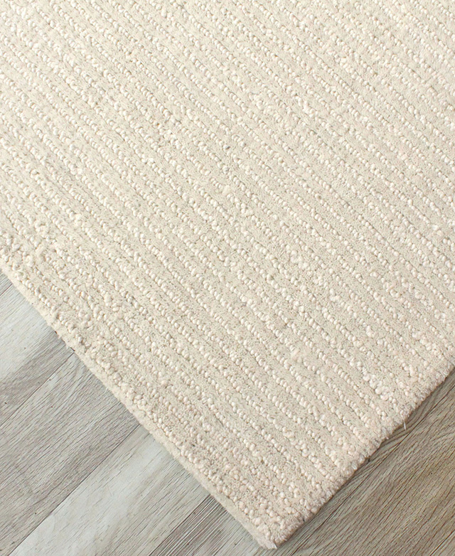 The bird's eye view of the corner of the rug highlights the subtle stripe and its two textures.