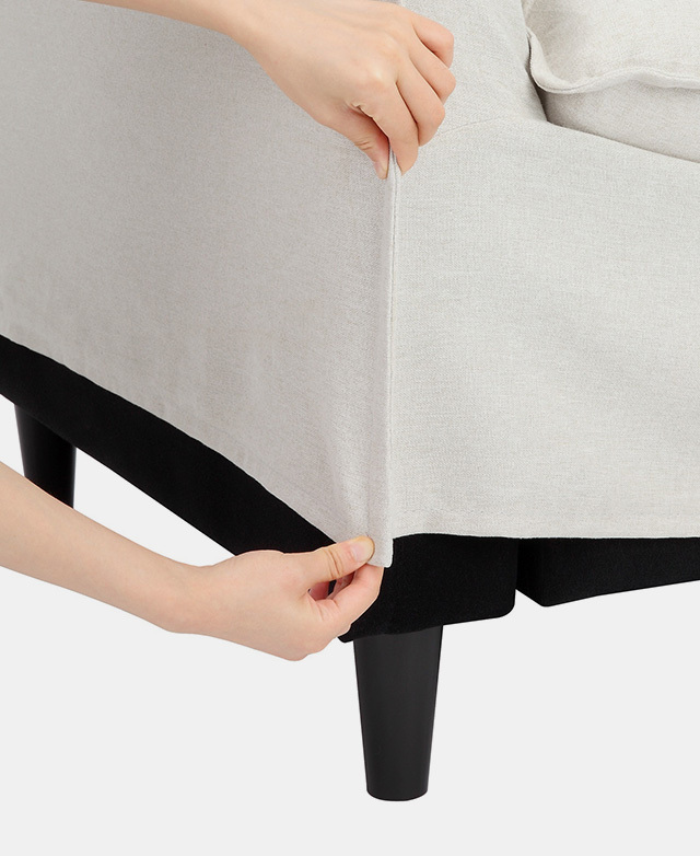 A pair of hands are depicted lifting the sofa cover away from the sofa structure beneath.