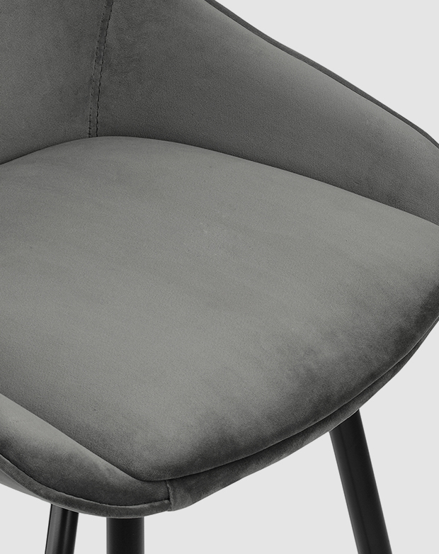 Bird's-eye view of a barstool seat. The deep seat has grey velvet upholstery and a padded base cushion. Bird's-eye view of a barstool seat. The deep seat has grey velvet upholstery and a padded base cushion.