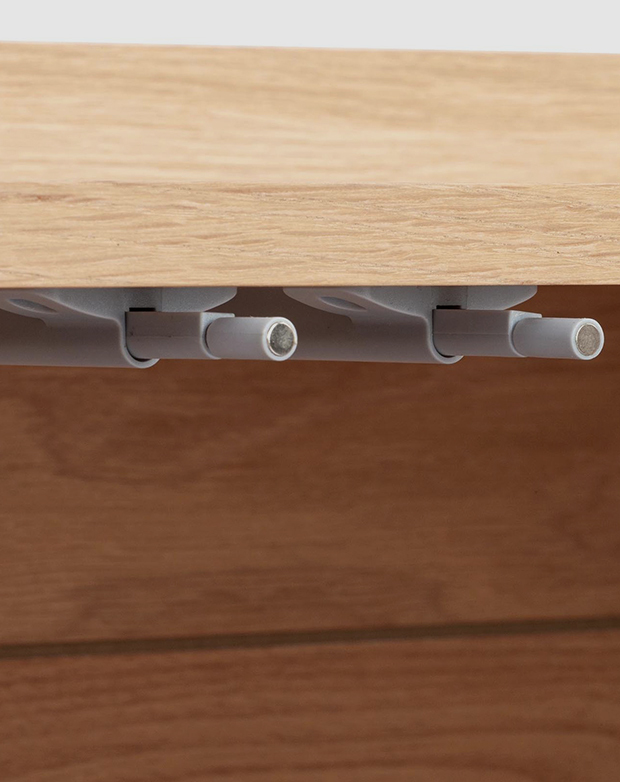Close up of the push release hardware underneath the table top, that allows for a soft close of the cabinet doors.