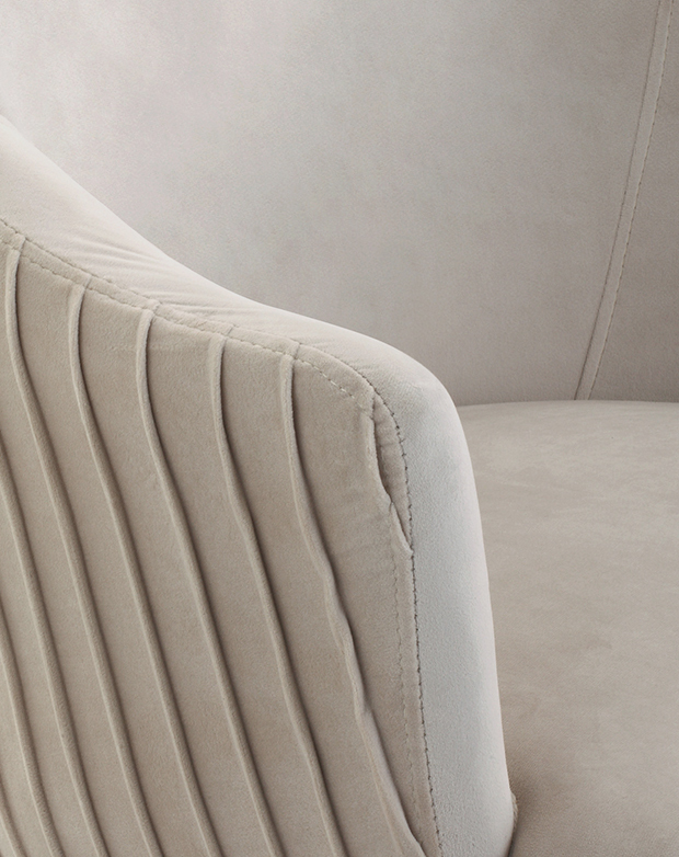 Zooming in on the armrest shows the pleated detail of the upholstery that extends around the exterior of the chair.