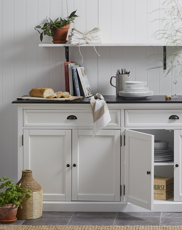 Sitting flush up against a panelled white wall, the sideboard is being utilised as an extra serving area.