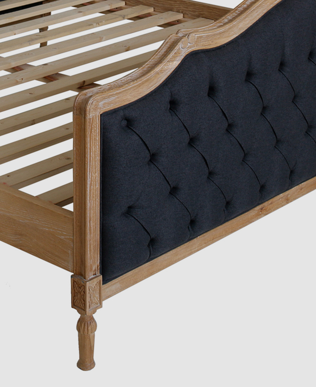 The footboard of a bed frame has black Dacron upholstery with diamond button tufting and folded pleats. The footboard of a bed frame has black Dacron upholstery with diamond button tufting and folded pleats.