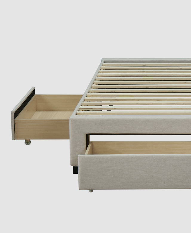 The bed frame is assembled but bare, with an end and a side drawer pulled out, as shown from the front angle.