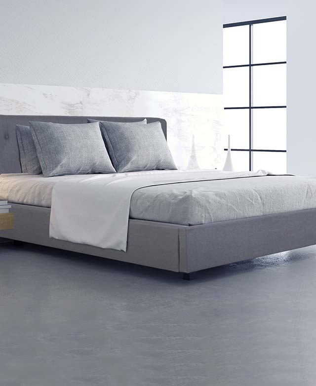The bed is dressed with grey tones, in a light room with a grey floor and white marbled wall.