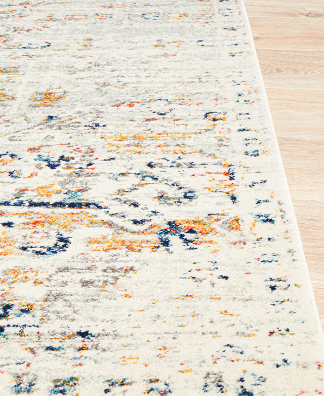 A close-up showing the rug's detail, with bursts of orange, navy, pink, and aqua on a cream background.