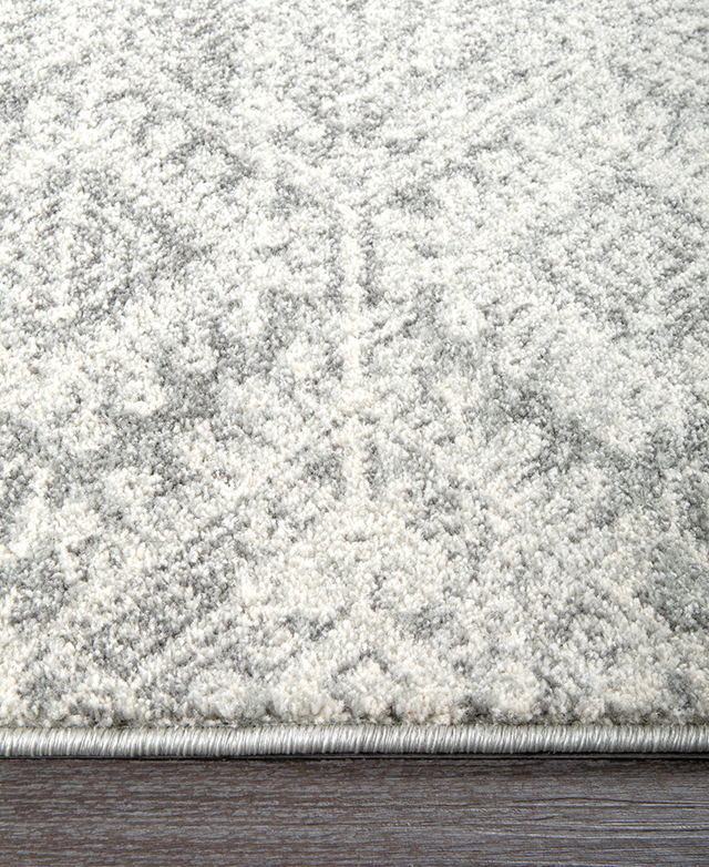 The 10mm pile height and thick, silver serged edges of the rug are shown from up close.