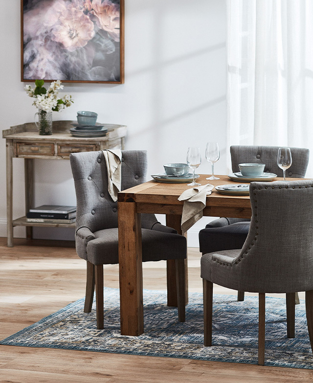 Three elegant dining chairs with grey wash upholstery are at a solid timber dining table in a French provincial interior. Three elegant dining chairs with grey wash upholstery are at a solid timber dining table in a French provincial interior.