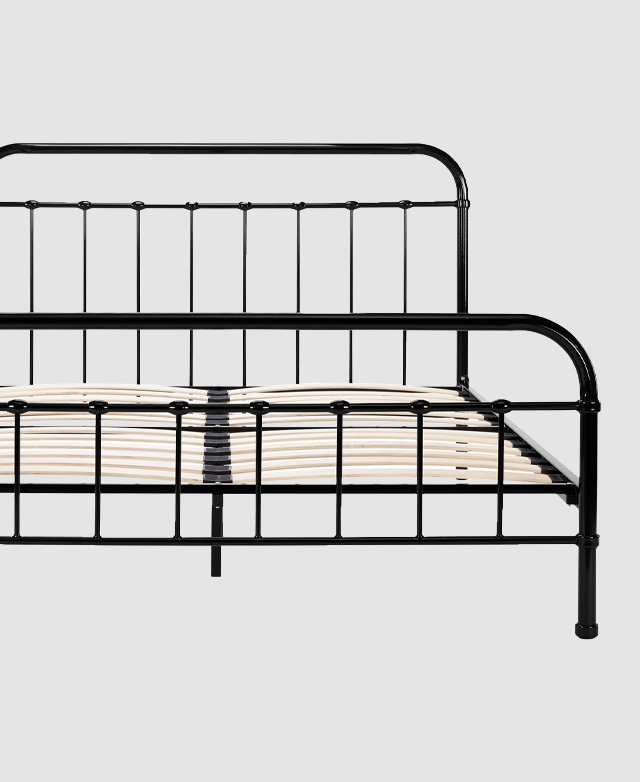 The front-on angle of the undressed bed frame highlights the bed's vertical bars of the bedhead and foot-end.
