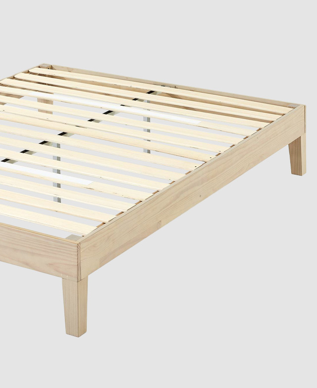 A high angle shows a portion of the unmade bed base, where clean lines of the edges and the neat slats are visible.