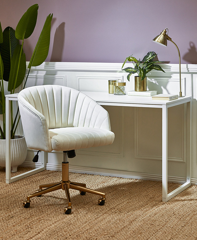 Next to a simple white desk in front of a panelled wall, the chair's white upholstery and metallic base are displayed.