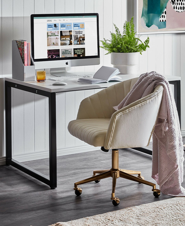 The chair, shown from the side and in front of a monochrome office desk, has a pink blanket draped over the back.