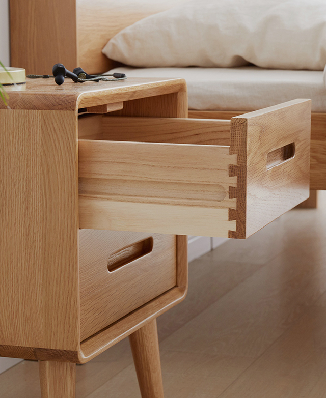 The top drawer of the timber bedside table is pulled out, revealing its spacious depth.