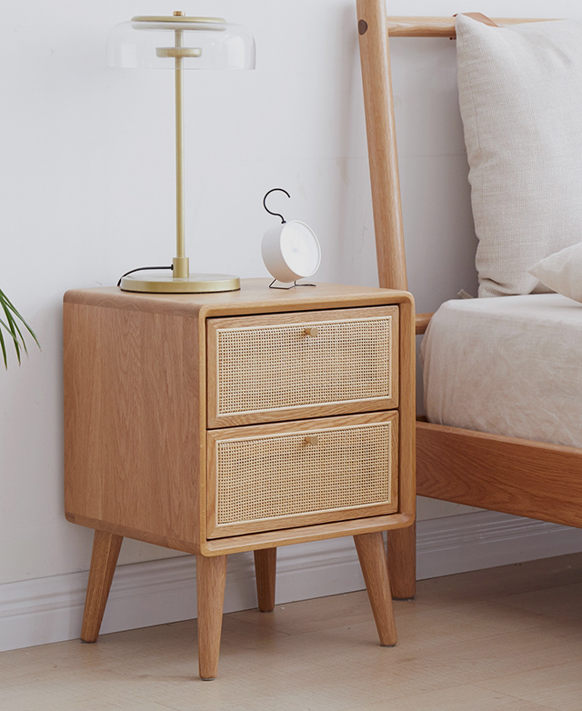 The side table in situ with a simple lamp and alarm clock on top in a minimalist, Scandi-inspired bedroom setting.