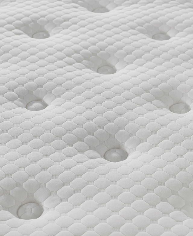 Honeycomb pattern of the knitted fabric, with button tufting, is shown up close.