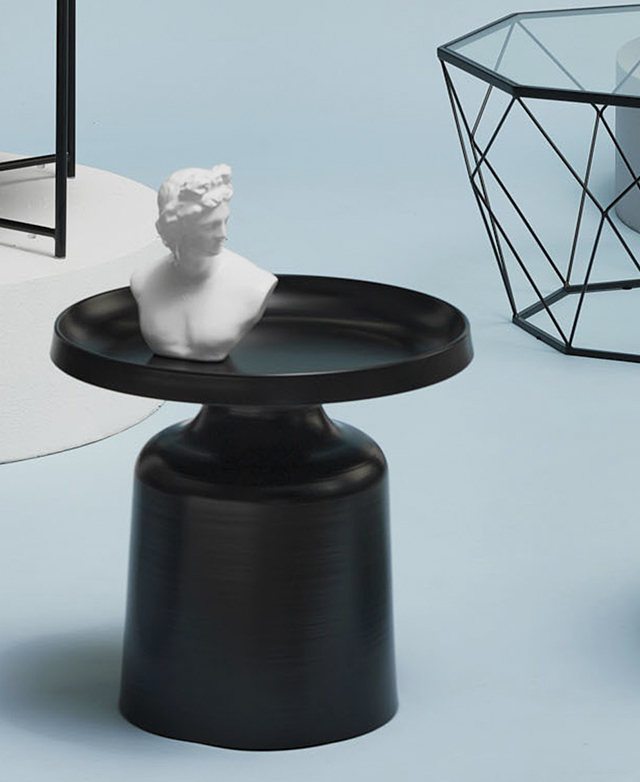 A white bust sits on top of the solid side table, drawing attention to the subtle sheen of the black powder-coated steel.