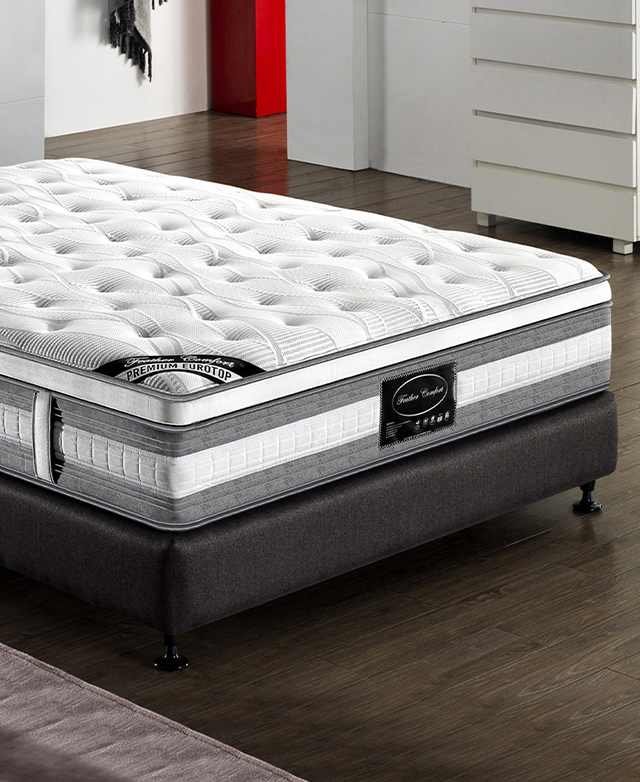 A premium mattress with layers of high-density foam is placed on top of a black bed base in a bedroom setting.