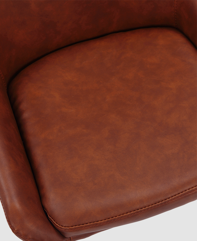 Bird's-eye view of the base cushion of a dining chair with tan faux leather upholstery.