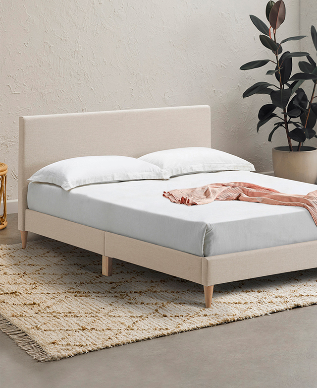 A side angle displays the light timber colour and elegantly tapered shape of the bed's legs.