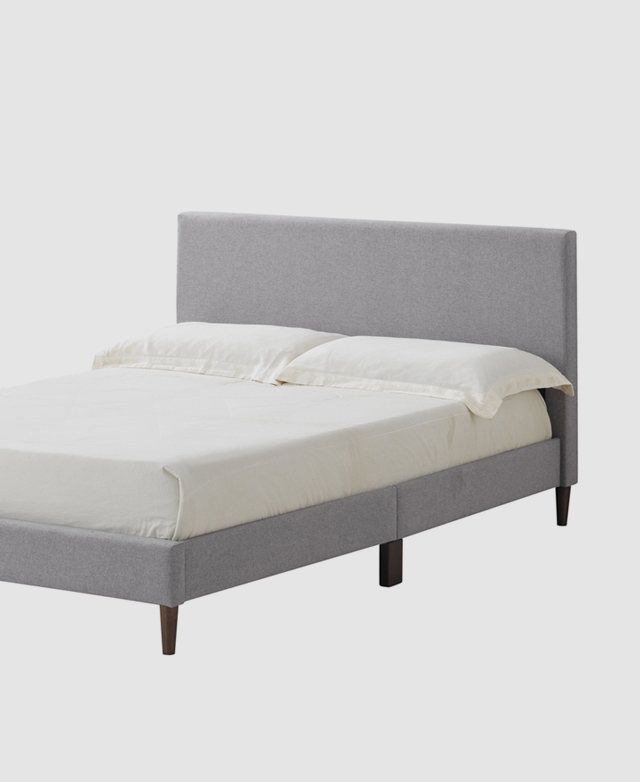 A three quarter angle shows the bed made and dressed with simple cream sheets and two standard pillows. A three quarter angle shows the bed made and dressed with simple cream sheets and two standard pillows.