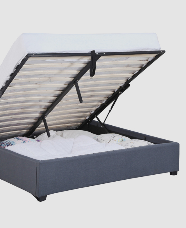 The bed's slatted support is lifted up, with a mattress on it, to reveal storage space that holds bedding.