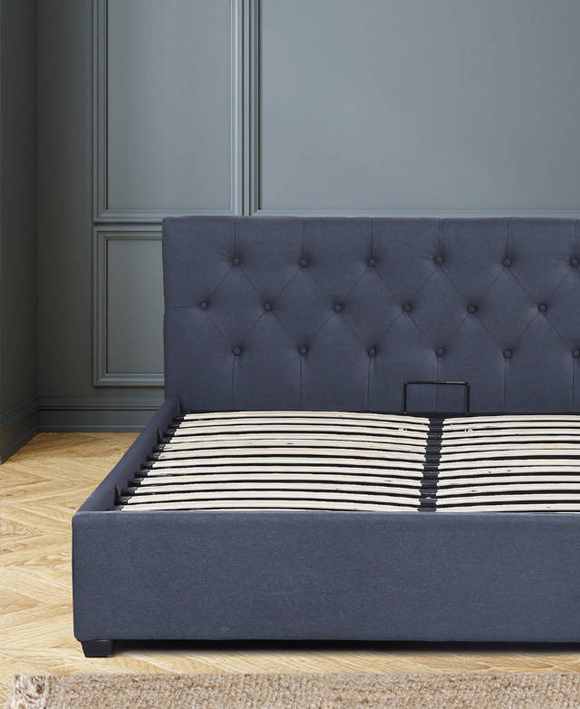 The bed frame is in front of a blue-grey panelled wall on a parquet wood floor.