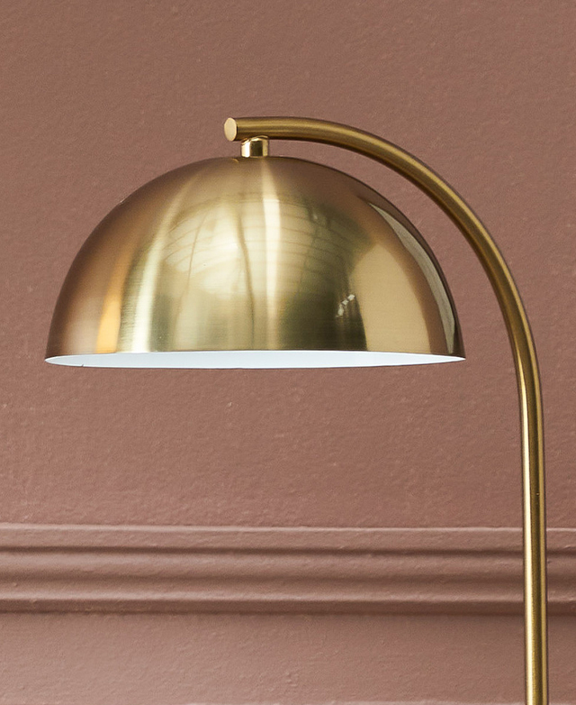 The top half of a lamp. Made of metal in a brass finish, a slender arm arches up to connect to the semi-circle lamp shade.