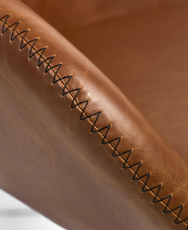 Zooming in on the chair's armrest shows the black, zigzag stitching decorating the perimeter of the seat. Zooming in on the chair's armrest shows the black, zigzag stitching decorating the perimeter of the seat.