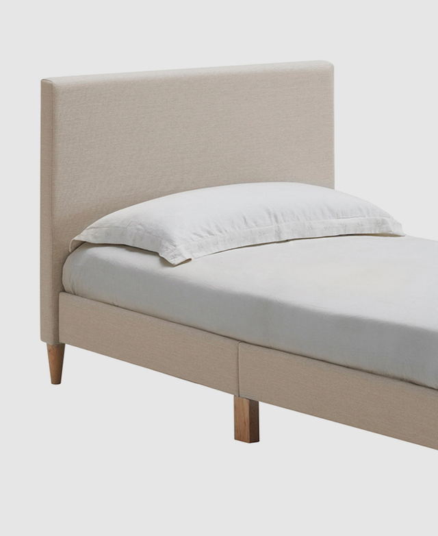 The top half of a single-size bed is shown from an angle, highlighting its simple, streamlined design.