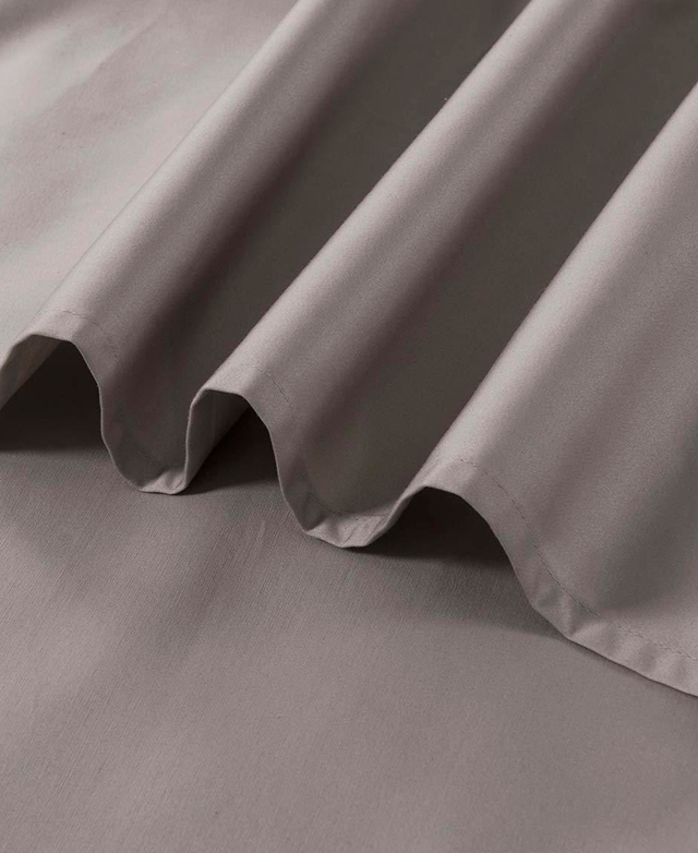 The smooth texture of a taupe-coloured fitted sheet and flat sheet is shown.