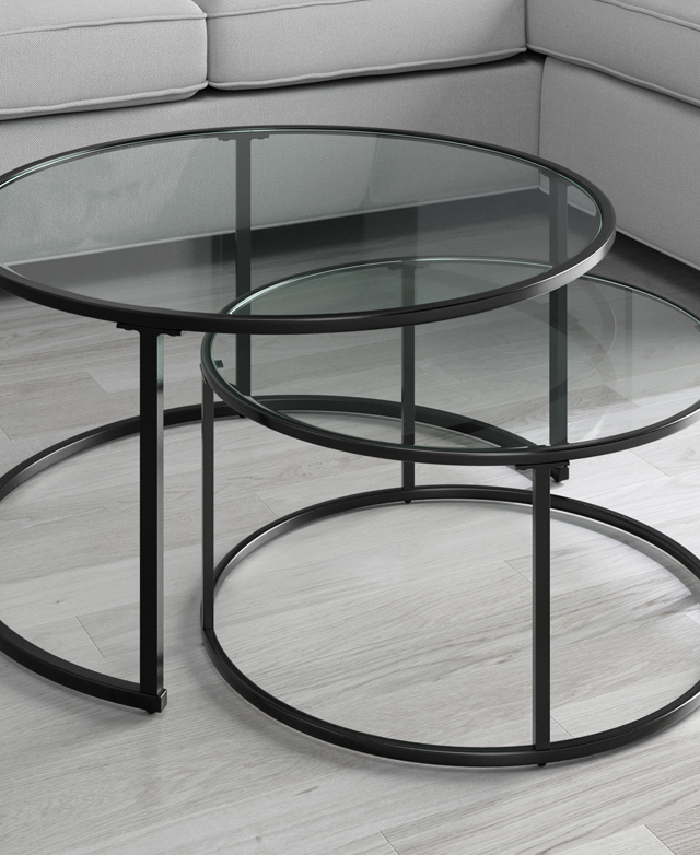 A monochrome room contains the tables partially nestled together. A sofa is in the background. A monochrome room contains the tables partially nestled together. A sofa is in the background.