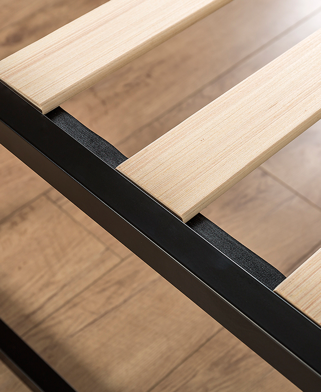 A close-up of the base shows flat plywood slats, evenly spaced apart and affixed to the steel frame.