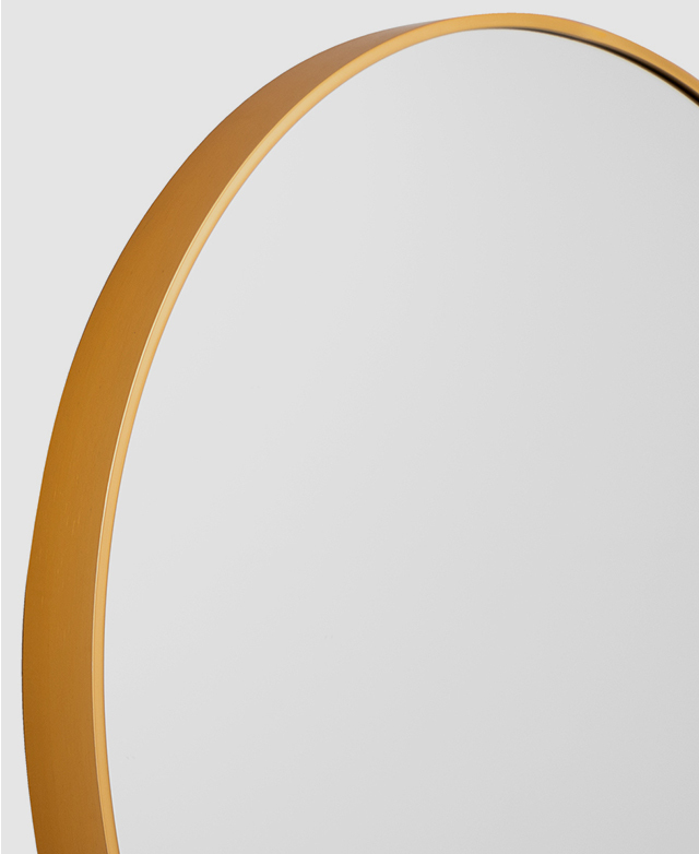 Angled view of a circular mirror with a slender gold aluminium frame. Angled view of a circular mirror with a slender gold aluminium frame.