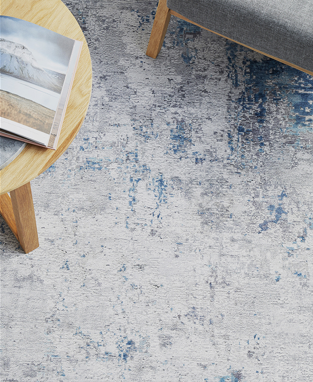 Bird's-eye view of a blue grey rug styled underneath timber furniture.