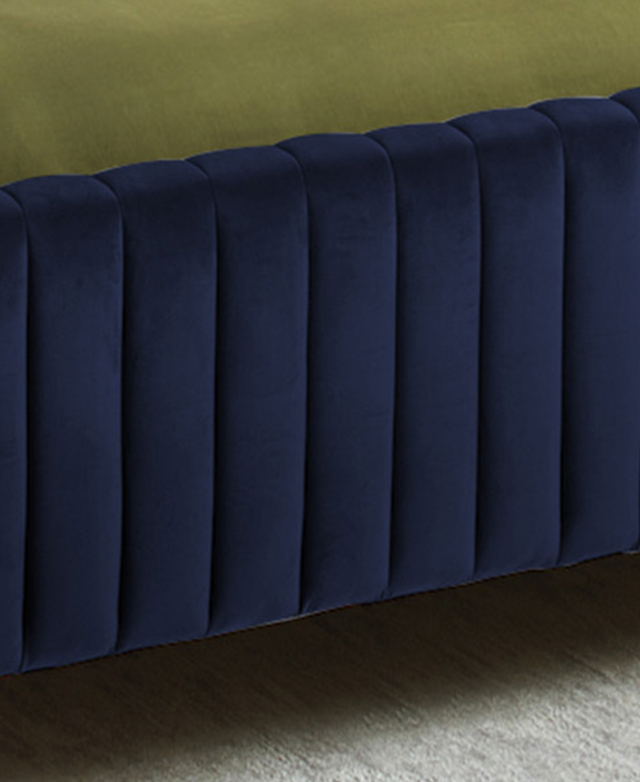 The cropped image zooms in on the footboard, which is upholstered in rich, blue velvet. The bedding just in shot is green. The cropped image zooms in on the footboard, which is upholstered in rich, blue velvet. The bedding just in shot is green.