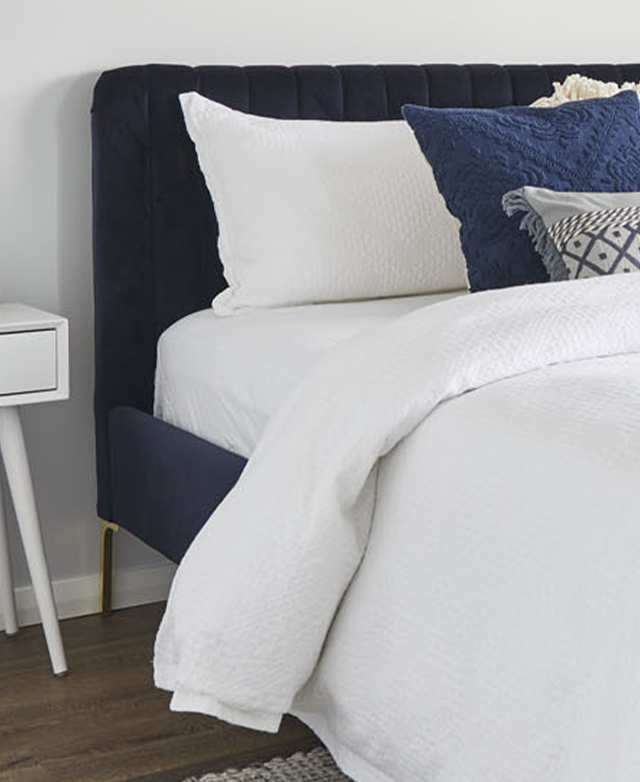 The bed is dressed with crisp white sheets and blue cushions, which brings out the depth of the bedhead. The bed is dressed with crisp white sheets and blue cushions, which brings out the depth of the bedhead.