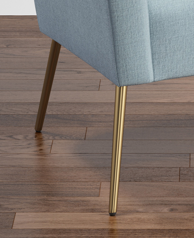 Gold stainless steel legs in a tapered shape splay outwards from underneath the base of the chair. Gold stainless steel legs in a tapered shape splay outwards from underneath the base of the chair.