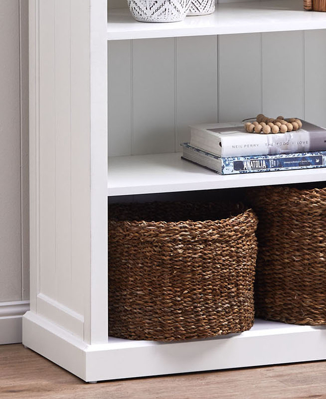 A white shelving unit has two wicker storage baskets on the lower shelf.