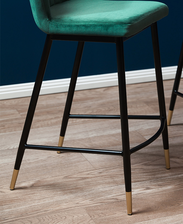 The black powder-coated steel frame features a built-in footrest and gold tips at the end of each leg.