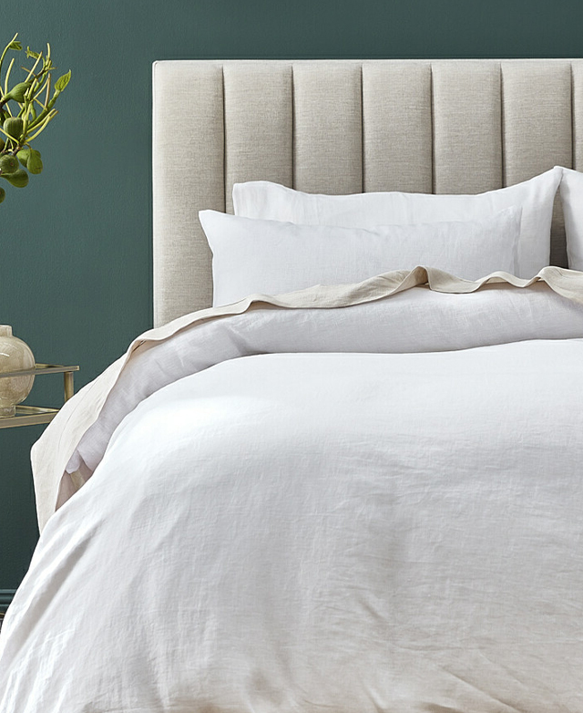 A front angle shows the bed dressed sumptuously in neutral tones, with the panelled bedhead visible behind the pillows.