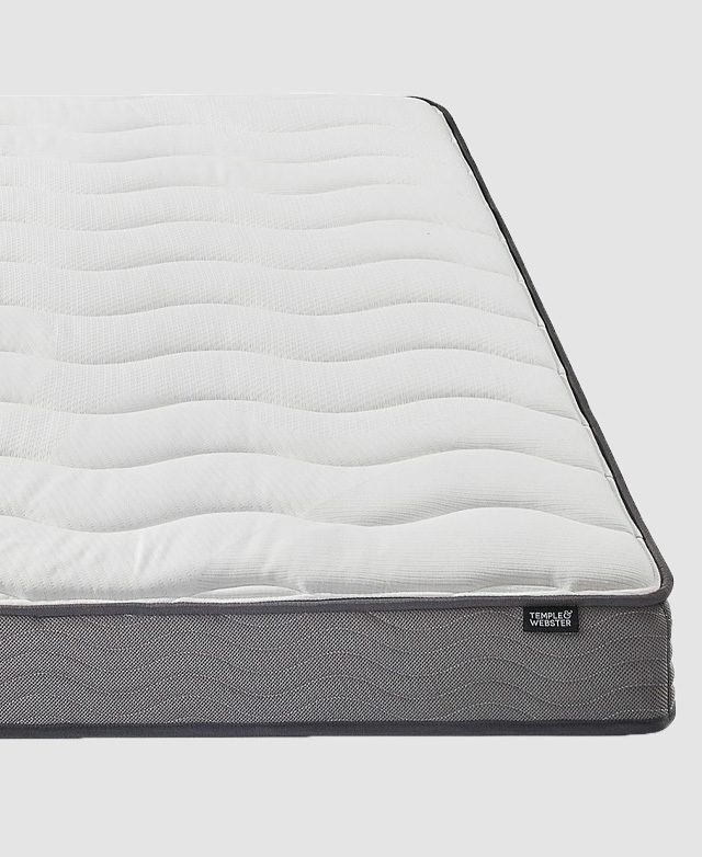 A mattress with thick grey piping trims around the periphery, and a wavy quilted fabric top.
