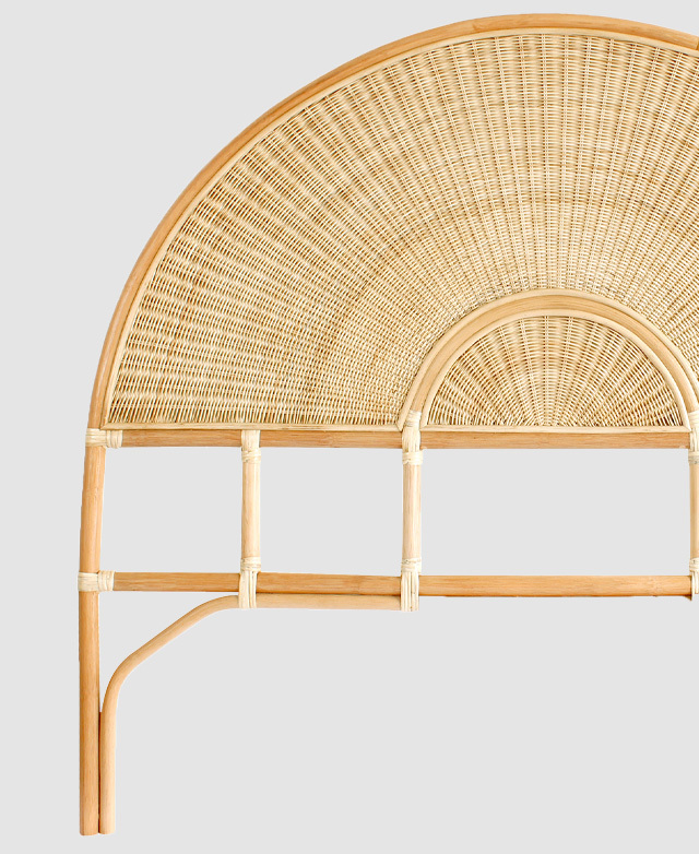 A freestanding bedhead with an arched shape. The rattan panel has a tightly woven wicker texture.