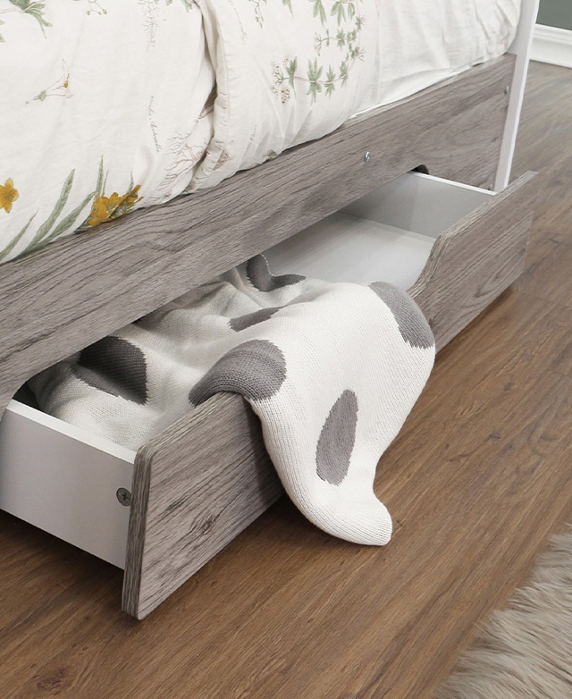 The drawer underneath the bottom bunk is pulled out, revealing a knitted blanket stored inside.