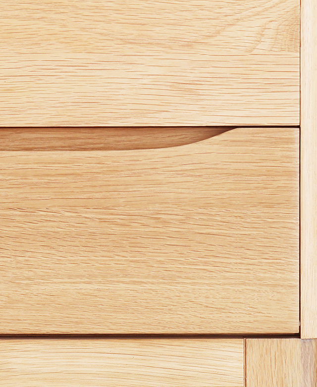 The front face of the bedside table's two drawers are in focus, illustrating the straight grain of solid American oak wood.