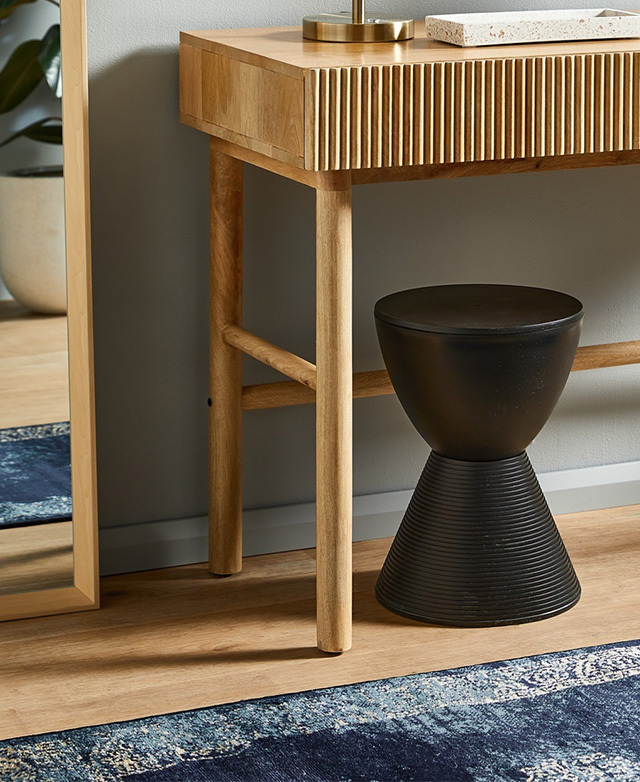 The mango wood writing desk in situ, with a black stool in an hourglass shape tucked underneath.