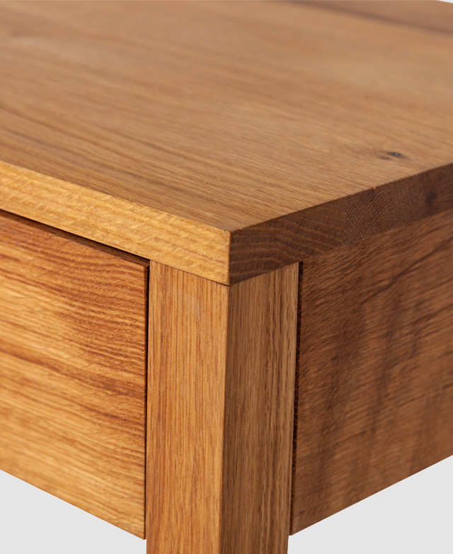 Zooming in on one corner of the table top accentuates the golden hue and straight grain of solid oak wood.