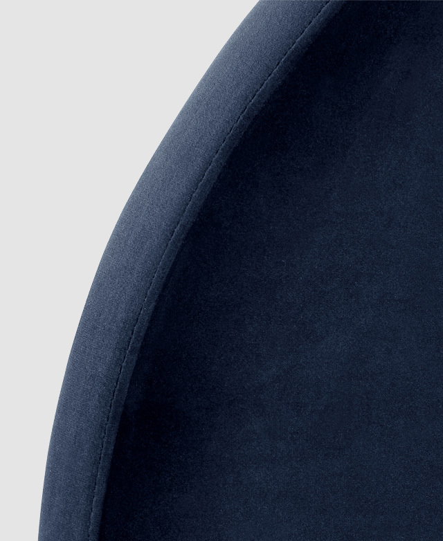 Large-scale view of the rounded edge of an arch blue velvet bedhead.