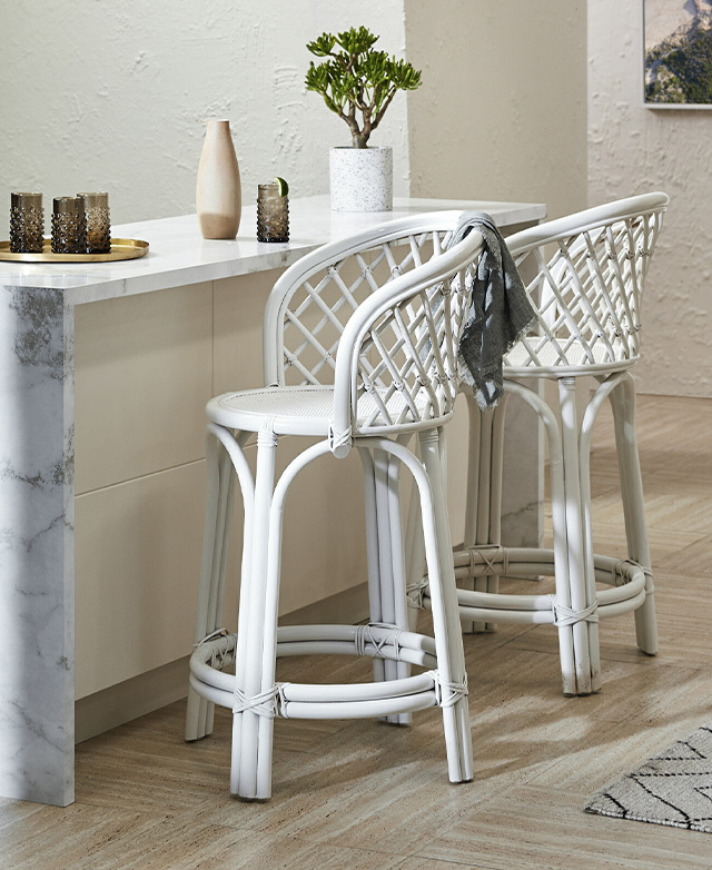 Two of the white counter stools in situ at a kitchen countertop, creating an elegant, farmhouse chic look.