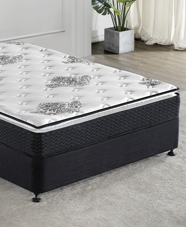 A black bed base with a thick mattress on top is styled above a grey carpet.