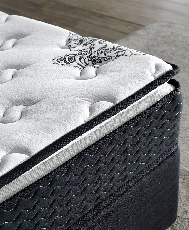 Close-up angle of the corner of a mattress. It has multiple layers of support, and thick black piping around the edges.